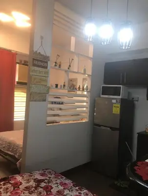 a room with a shelf with wine bottles on a wall at Cozy Starpad14R Stamford McKinley Hill in Manila