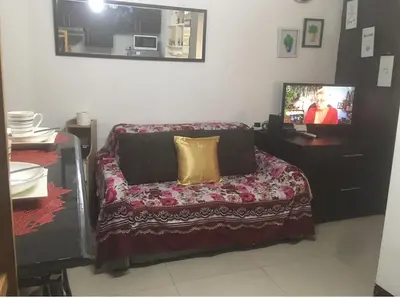 a living room with a couch and a tv at Cozy Starpad14R Stamford McKinley Hill in Manila