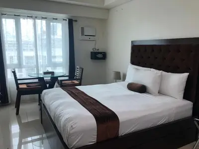 a bedroom with a large bed and a table at Studio unit at The Beacon Makati near Greenbelt in Manila