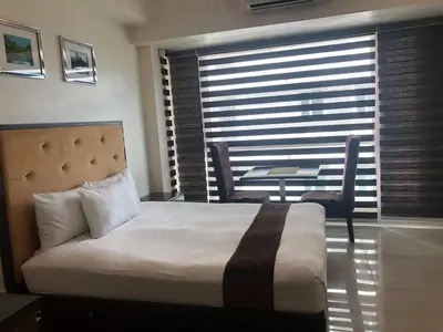 a hotel room with a bed and a table and chairs at Studio unit at The Beacon Makati near Greenbelt in Manila