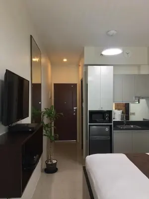 a room with a bed and a kitchen with a television at Studio unit at The Beacon Makati near Greenbelt in Manila
