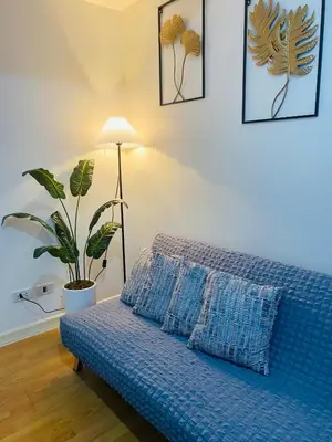 a blue couch in a room with a potted plant at cozy and minimalist room near airport in Manila