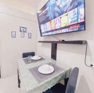 a dining room table with a tv on the wall at Sea Residences by Jan & Val Alano in Manila