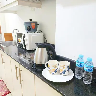 a kitchen counter with two coffee cups and water bottles at Sea Residences by Jan & Val Alano in Manila