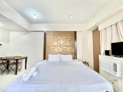 a bedroom with a large white bed and a desk at Cozy Spacious Condo Hotel near NAIA Manila Airport Pasay in Manila