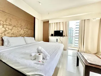 a hotel room with a bed with towels and a tv at Cozy Spacious Condo Hotel near NAIA Manila Airport Pasay in Manila