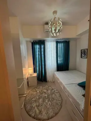 a bedroom with a bed and a rug and a chandelier at BH Crib - Staycation near Mall of Asia Complex in Manila