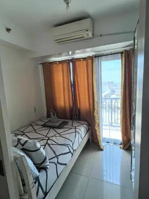 a small bedroom with a bed and a large window at BH Crib - Staycation near Mall of Asia Complex in Manila