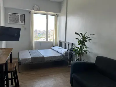 a living room with a bed and a window at Studio Getaway in Alabang at Anuva Residences in Manila
