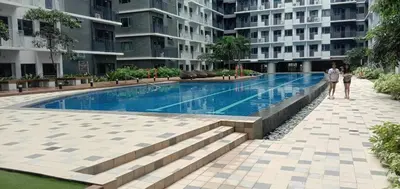 two people standing next to a swimming pool in a building at Cozy Private Condo at Shore 3 near MOA in Manila