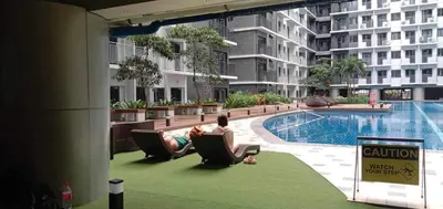 a person sitting in a chair next to a swimming pool at Cozy Private Condo at Shore 3 near MOA in Manila
