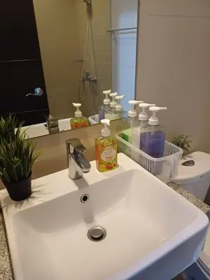 a bathroom with a white sink and a mirror at Cozy Pad BGC in Manila