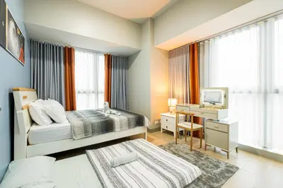 a bedroom with a bed and a desk with a television at Luxurious 2 Bedroom in Uptown BGC Taguig in Manila
