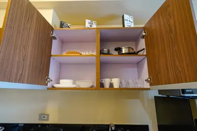 a kitchen with wooden cabinets with dishes on them at The Radiance Manila Bay Studio in Manila