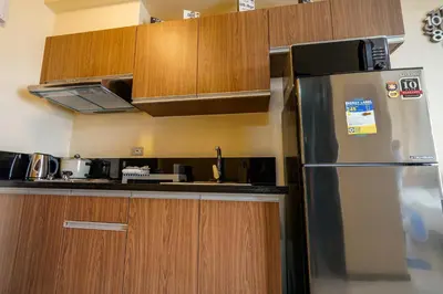 a kitchen with a stainless steel refrigerator and wooden cabinets at The Radiance Manila Bay Studio in Manila