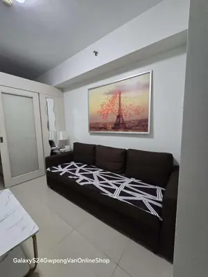 a living room with a couch and a painting on the wall at Sea Residences Yeshua infront of MOA Pasay in Manila