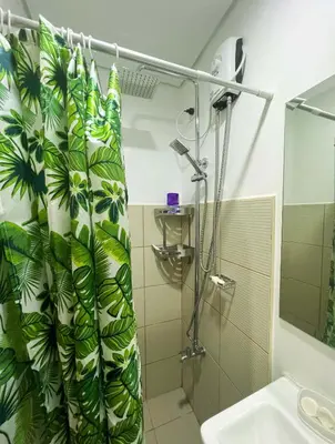 a bathroom with a shower curtain with green leaves at Samuel staycation in Smdc Green2 one studio unit in Dasmariñas