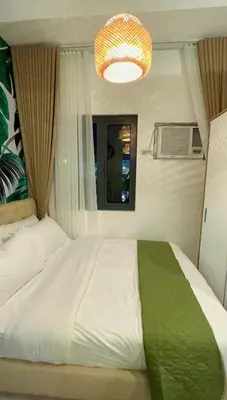 a bedroom with a large white bed and a chandelier at Samuel staycation in Smdc Green2 one studio unit in Dasmariñas