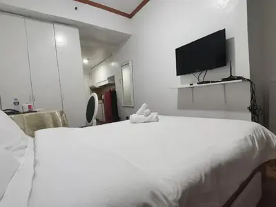 a bedroom with a large white bed and a flat screen tv at romantic makati in Manila
