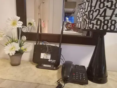 a desk with a phone and a lamp and flowers at Azure Urban Residence A11 Near Airport and SM Bicutan+ Free wifi in Manila