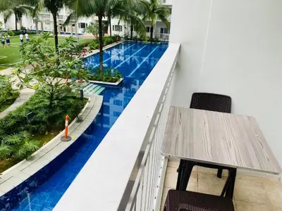 a balcony with a table and a swimming pool at SHORE RESIDENCE D15 shortwalk Mall of asia near airport in Manila