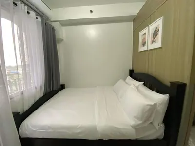 a bedroom with a bed with white sheets and pillows at SHORE RESIDENCE D15 shortwalk Mall of asia near airport in Manila