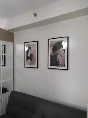 two framed pictures on a white wall with a couch at SHORE RESIDENCE D15 shortwalk Mall of asia near airport in Manila