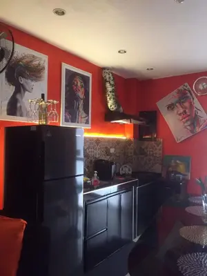 a kitchen with red walls and a black refrigerator at La Coccinella in Manila
