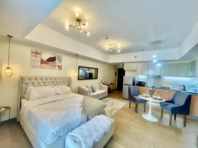 a bedroom with a bed and a living room at Cozy Place @ Venice Luxury Residences in Manila