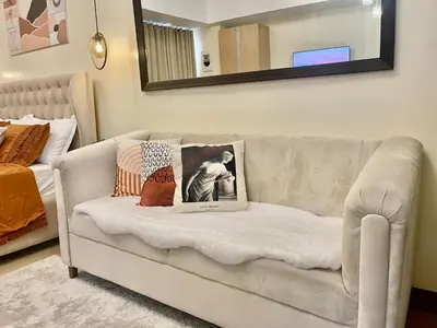 a white couch in a living room with a mirror at Cozy Place @ Venice Luxury Residences in Manila