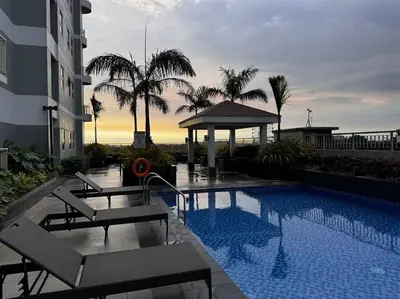 a swimming pool with chairs and a gazebo next to a building at Penthouse Lvl Luxury Cndo Nr MOA in Manila