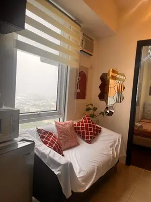 a bed with pillows in a room with a window at Kasara Resort Condotel by Vhi in Manila