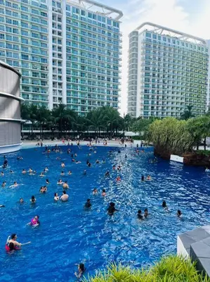 a group of people swimming in a large blue pool at Azure Urban Resort - St Tropez Tower Staycation Unit with a European Touch in Manila
