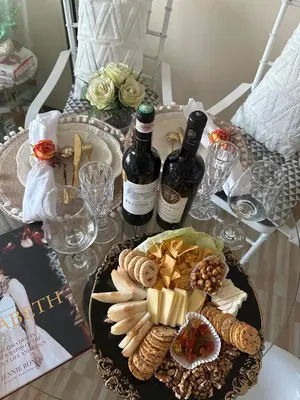 a table with a plate of food and two bottles of wine at Azure Urban Resort - St Tropez Tower Staycation Unit with a European Touch in Manila