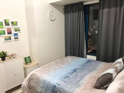 a bedroom with a bed and a window with a clock at Cozy 1-BR Flat in Air Residences Makati in Manila