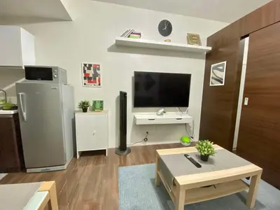 a living room with a television and a coffee table at Cozy 1-BR Flat in Air Residences Makati in Manila