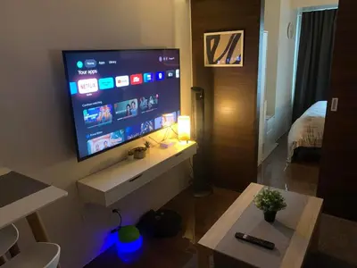 a living room with a large flat screen tv on a wall at Cozy 1-BR Flat in Air Residences Makati in Manila