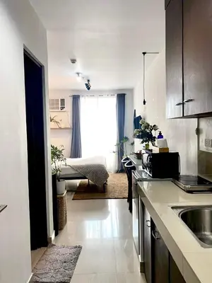 a kitchen with a sink and a living room at Cozy and nature inspired studio rooms Mandaluyong Edsa at F Residences under new management in Manila