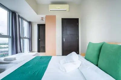 a bedroom with a green and white bed and windows at 2BR 2TB Uptown Parksuites BGC Balcony,fast WiFi,Washer in Manila