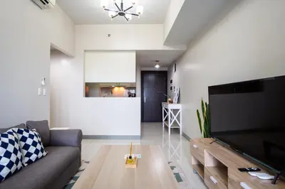 a living room with a couch and a large flat screen tv at 2BR 2TB Uptown Parksuites BGC Balcony,fast WiFi,Washer in Manila