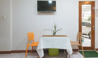 a table with chairs and a tv on a wall at Catlea Inn in Manila