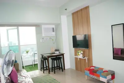 a living room with a tv and a table with chairs at The Beacon Makati by mvmtransient in Manila
