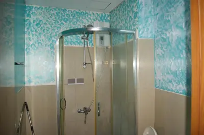 a shower in a bathroom with blue wallpaper at The Beacon Makati by mvmtransient in Manila