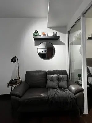 a living room with a brown leather couch and a mirror at Prime Posh Downtown Condo in Manila