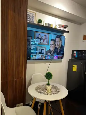 a room with a table and a tv on a wall at Prime Posh Downtown Condo in Manila