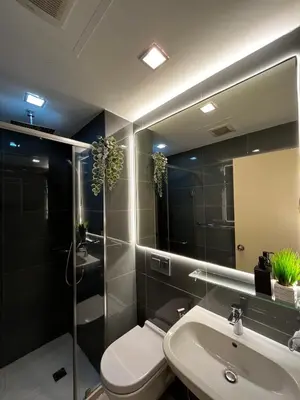 a bathroom with a sink and a toilet and a mirror at Prime Posh Downtown Condo in Manila