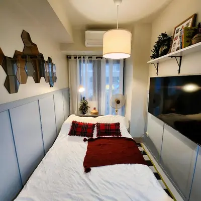 a small bedroom with a bed with a red blanket at My Humble Abode at Shore 3 in Manila