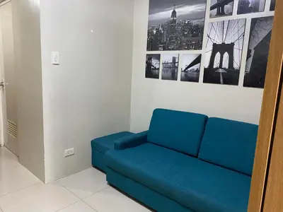 a blue couch in a room with pictures on the wall at Shell Residences C19 Shortwalk Sm Mall Of Asia Airport in Manila