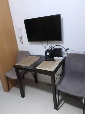 a desk with a monitor and two chairs and a computer at Shell Residences C19 Shortwalk Sm Mall Of Asia Airport in Manila