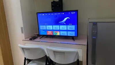 a computer monitor on a desk with two white chairs at Shell Residences C19 Shortwalk Sm Mall Of Asia Airport in Manila